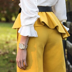 Michele Watches woman wearing a metallic grey watch with yellow frilly pants